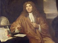 Man in brown robe next to a globe.