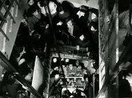 Large group of people on a staircase, all looking up, in a busy stairwell.